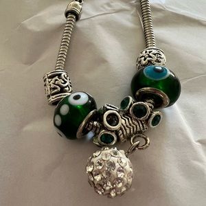 Charm bracelet. Emerald green color. Lobster clasp. Two stones missing.